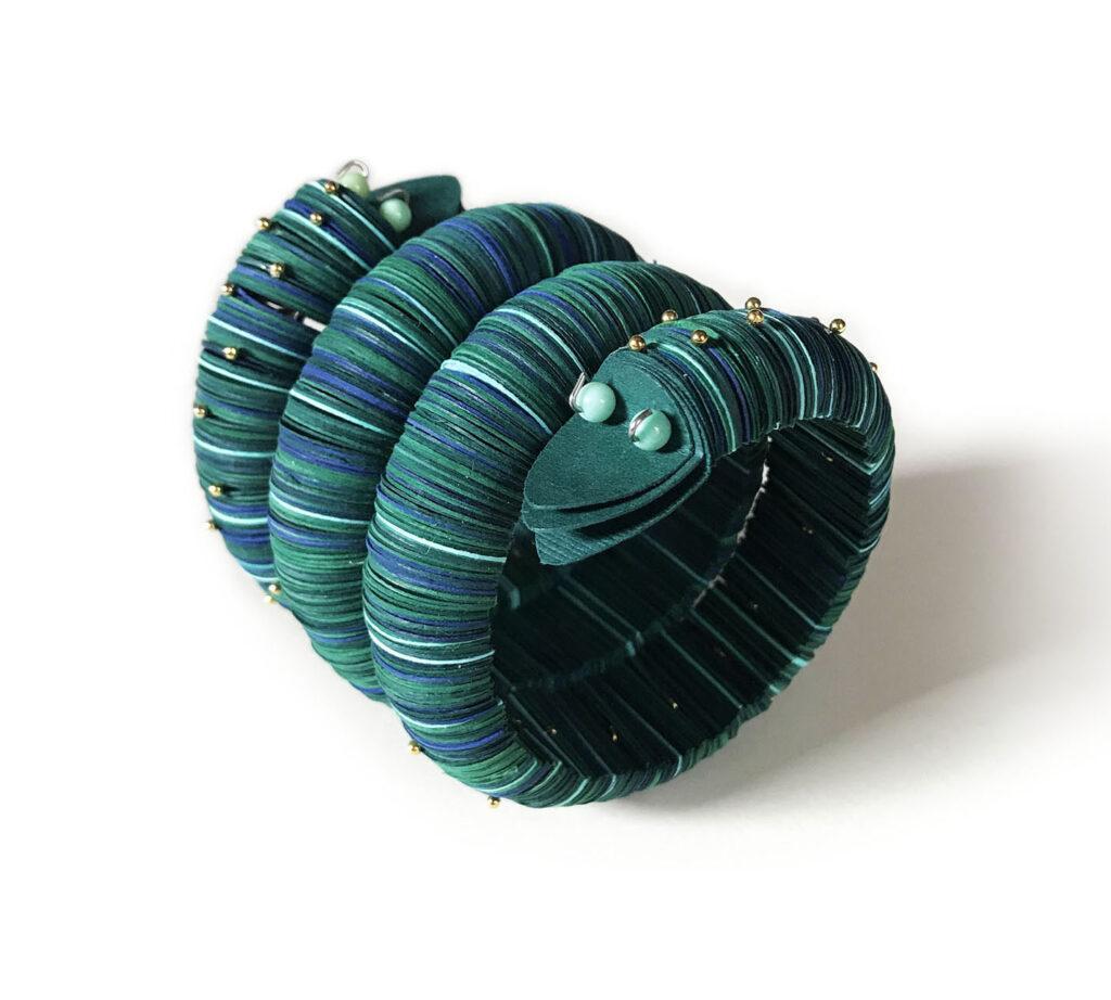 grande bracciale a forma di serpente con due teste fatto di carta nei toni del blu e del verde ed impreziosito con piccoli perni di metallo dorato, e perle di giada naturale