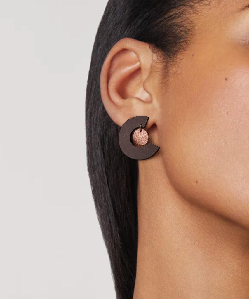 Model wearing brown-colored round stud earrings and copper-colored pendant