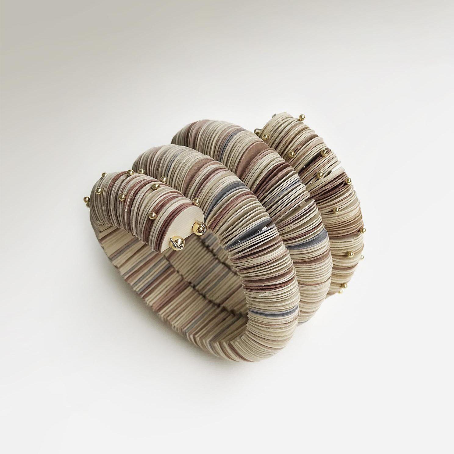 Bracciale elegante a serpente in colore chiaro fatto di carta con piccoli perni sferici dorati